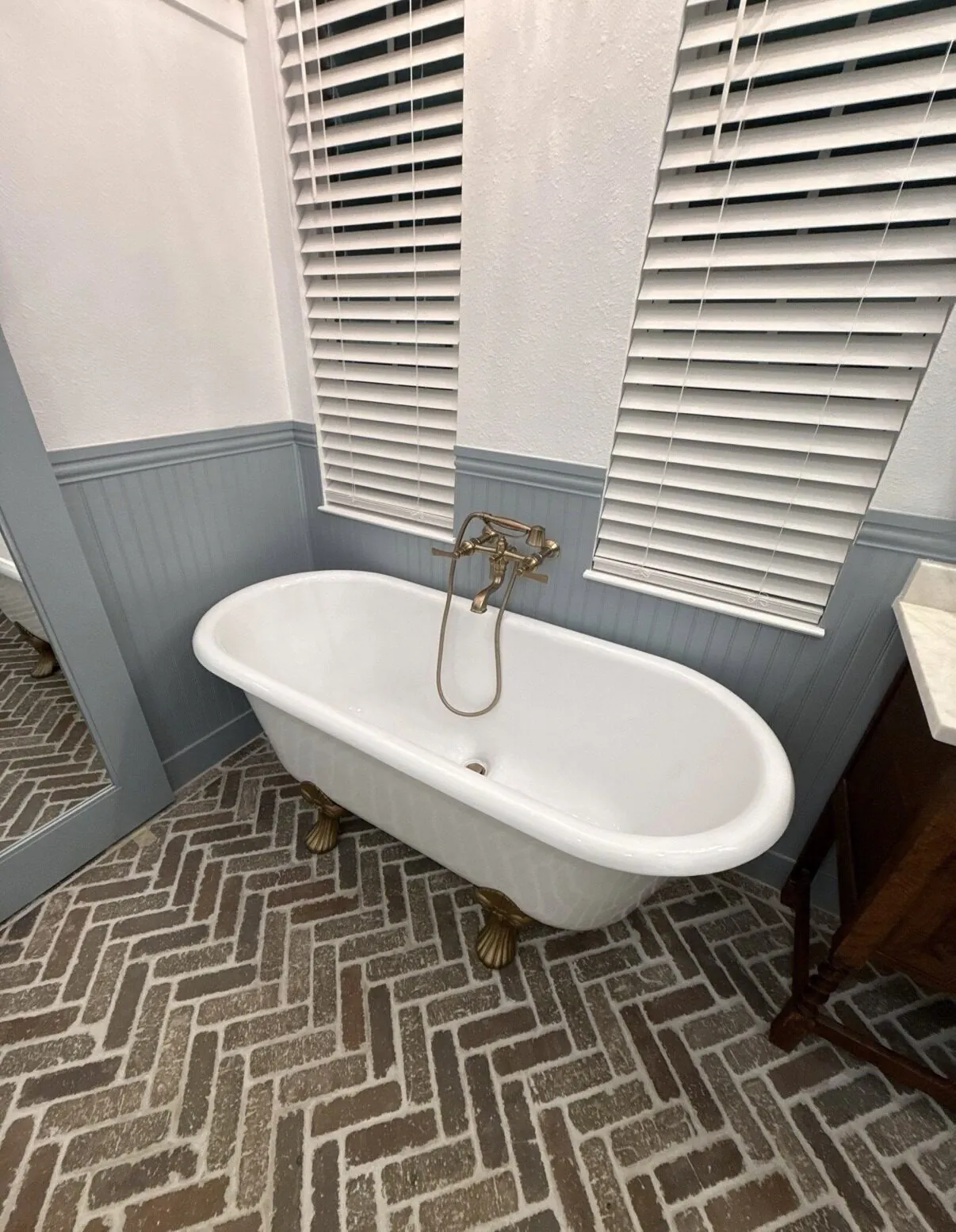 Finished bathroom with herringbone tile and a freestanding tub