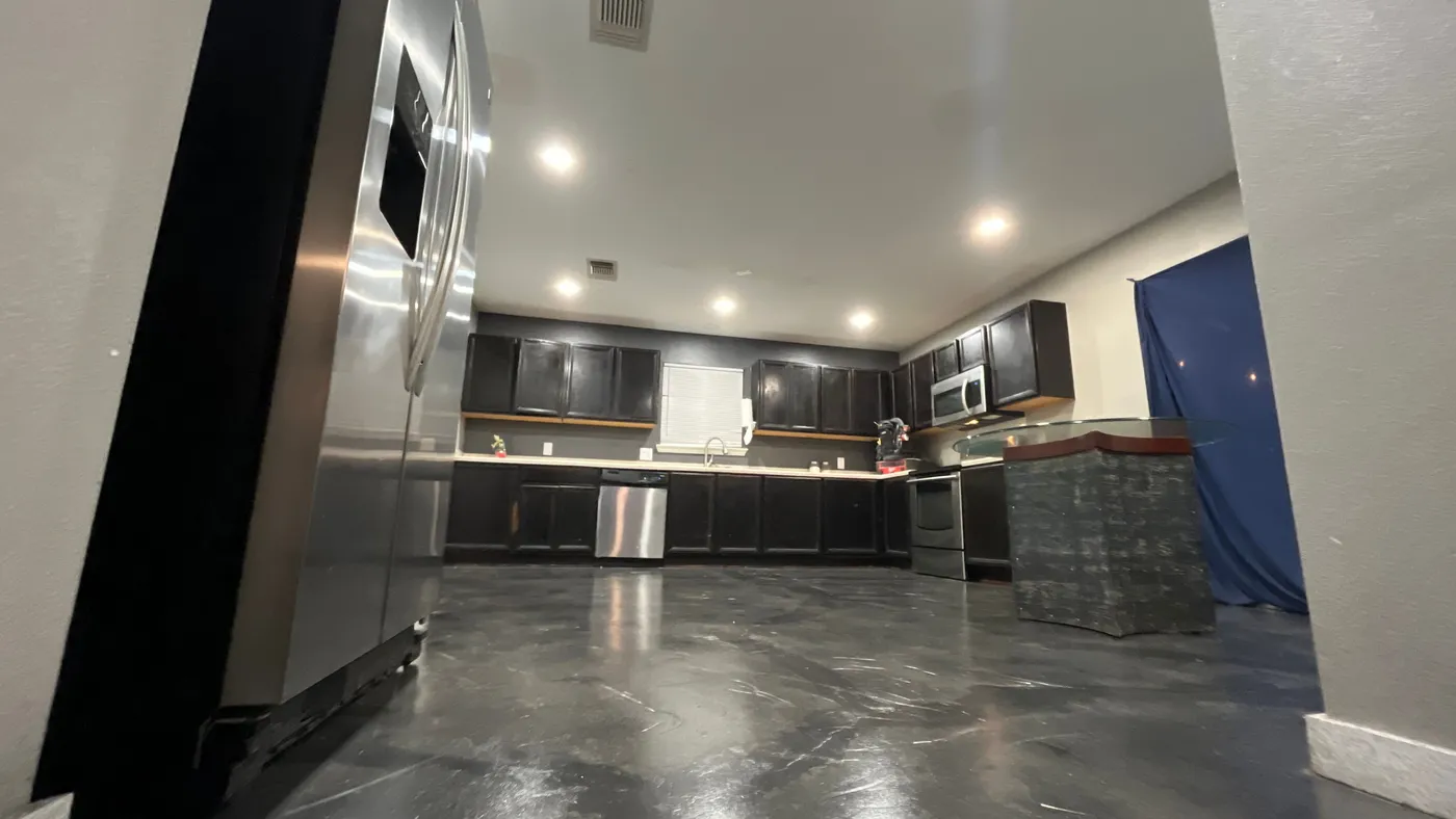 Metallic epoxy floor running through the kitchen with stainless appliances