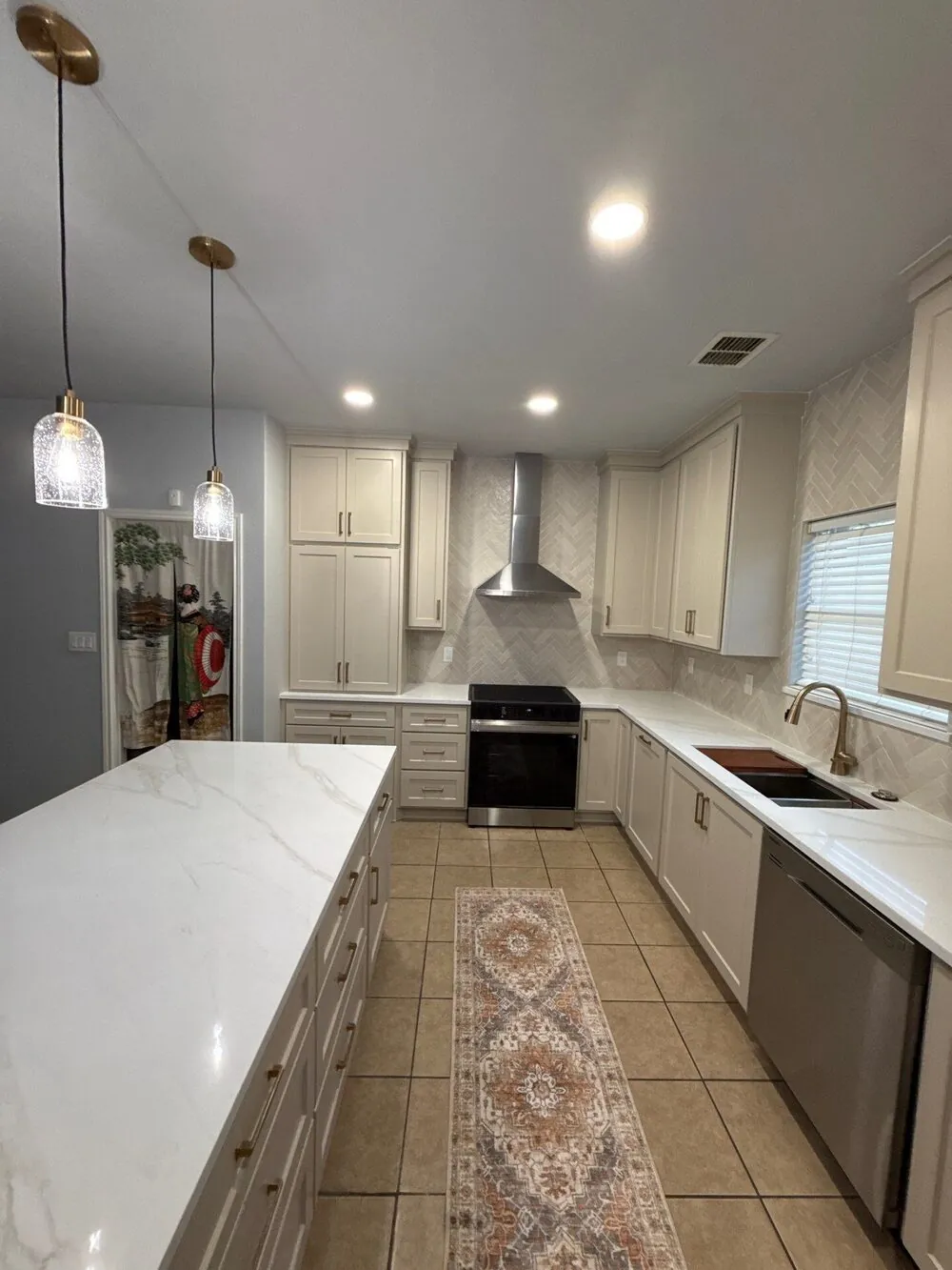 Island and perimeter counters with the range, vent hood and window beyond