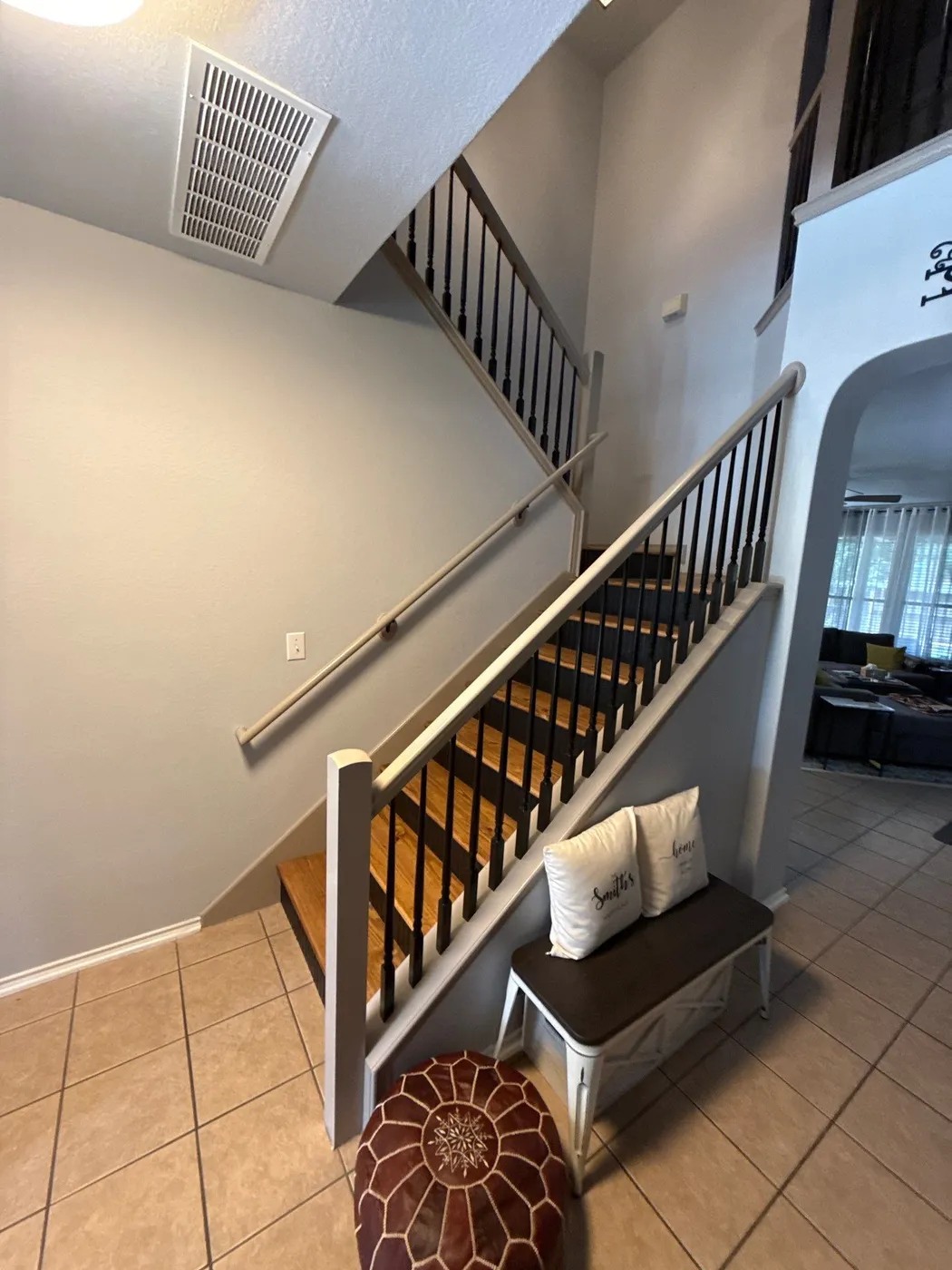 Finished staircase from the entry, with the arched living room beyond
