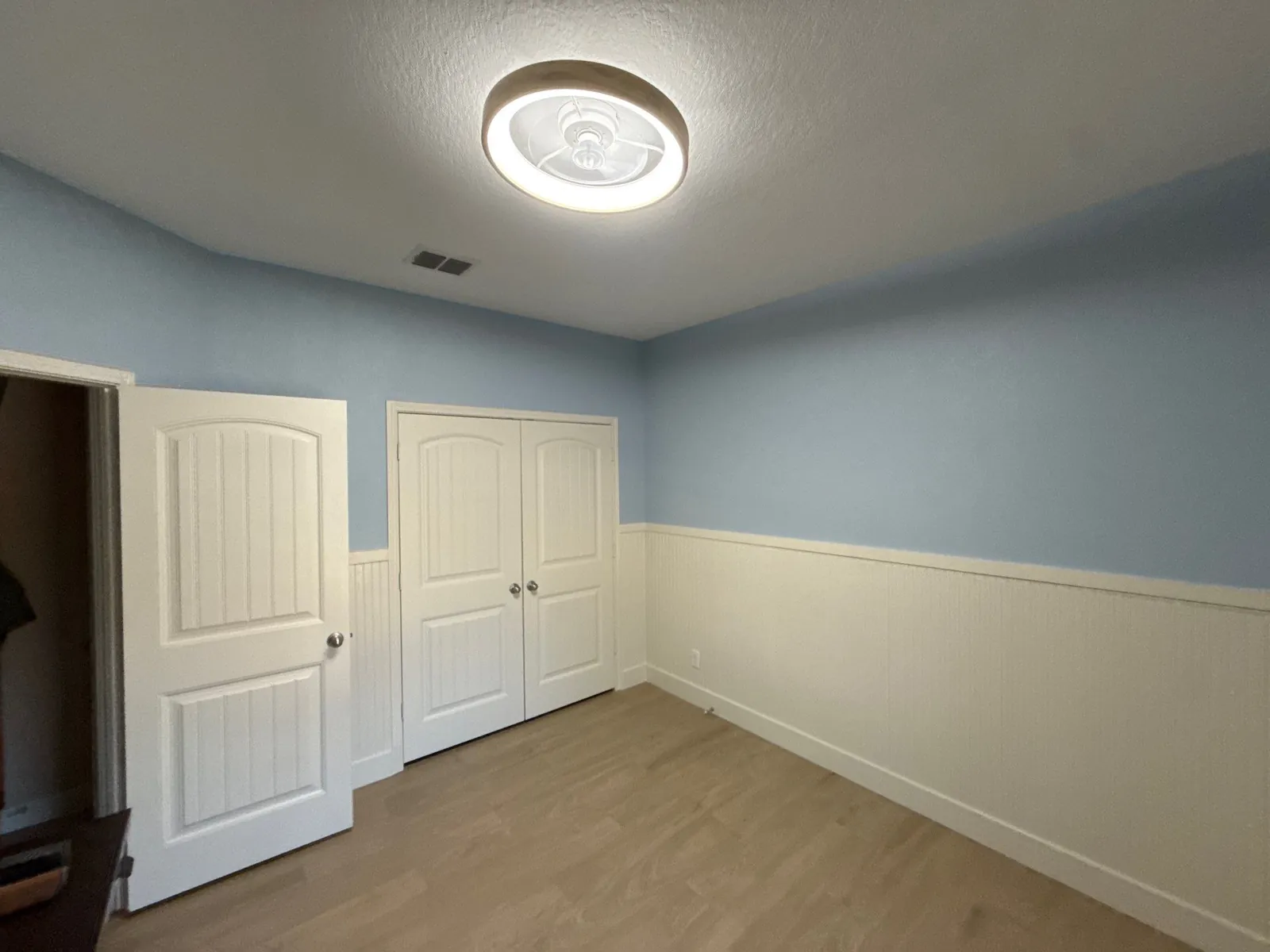 Panelled closet doors closed against the wainscot beside the room's entry door
