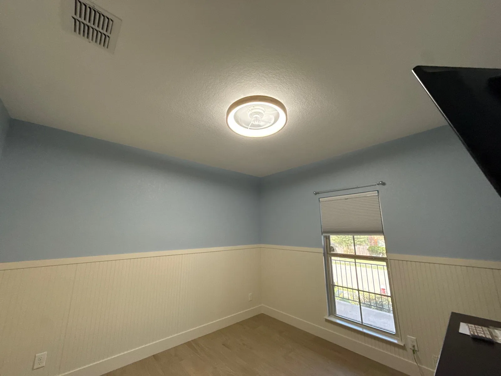 Upper corner of the room where the blue wall meets the ceiling above the wainscot cap rail