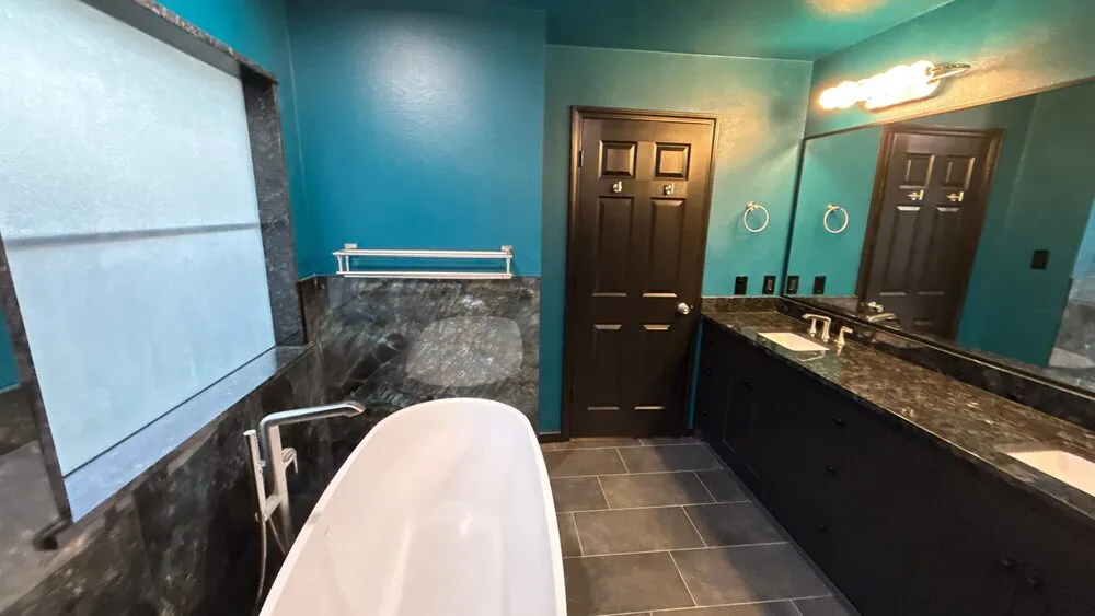 Freestanding tub set against a frosted window with a stone-tiled surround