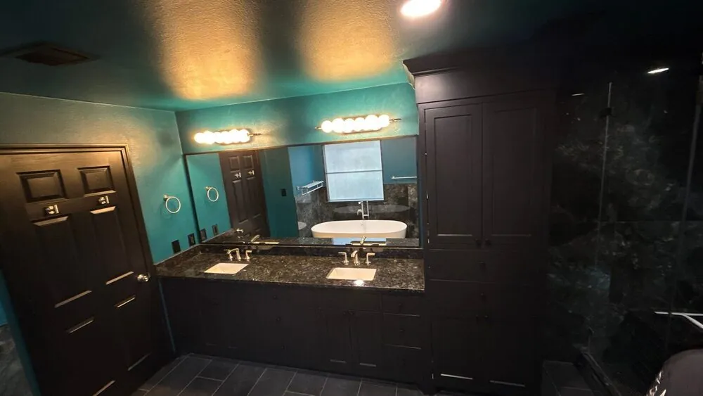 Vanity and mirror reflecting the freestanding tub across the room