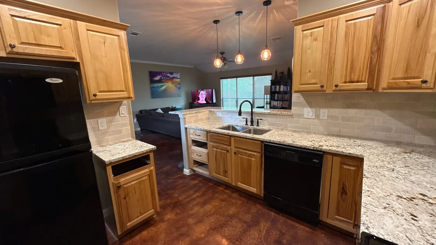 Kitchen corner with new countertops and tiled backsplash, looking through to the living room