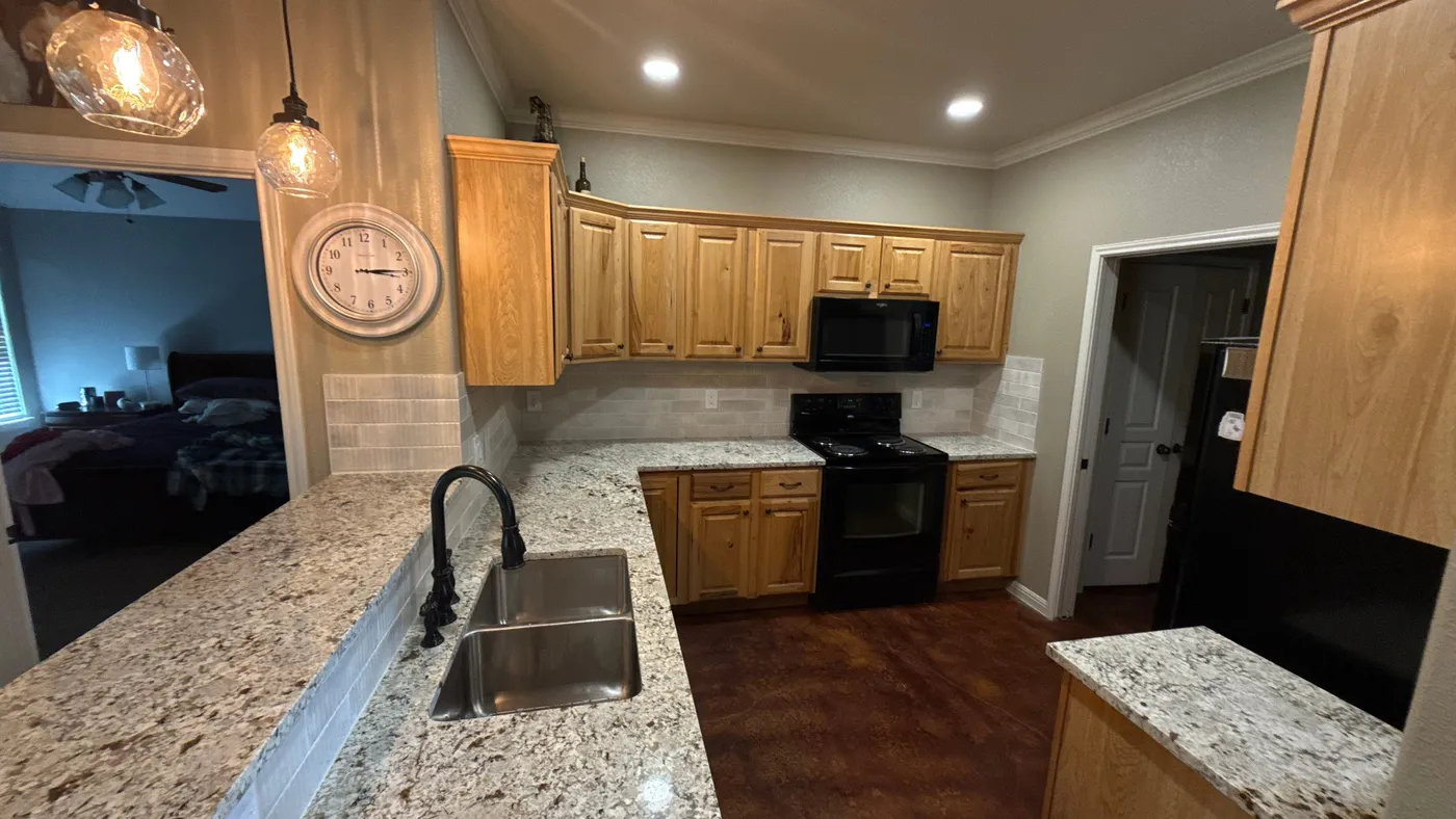 Counter run with the new backsplash and sink below pendant lighting