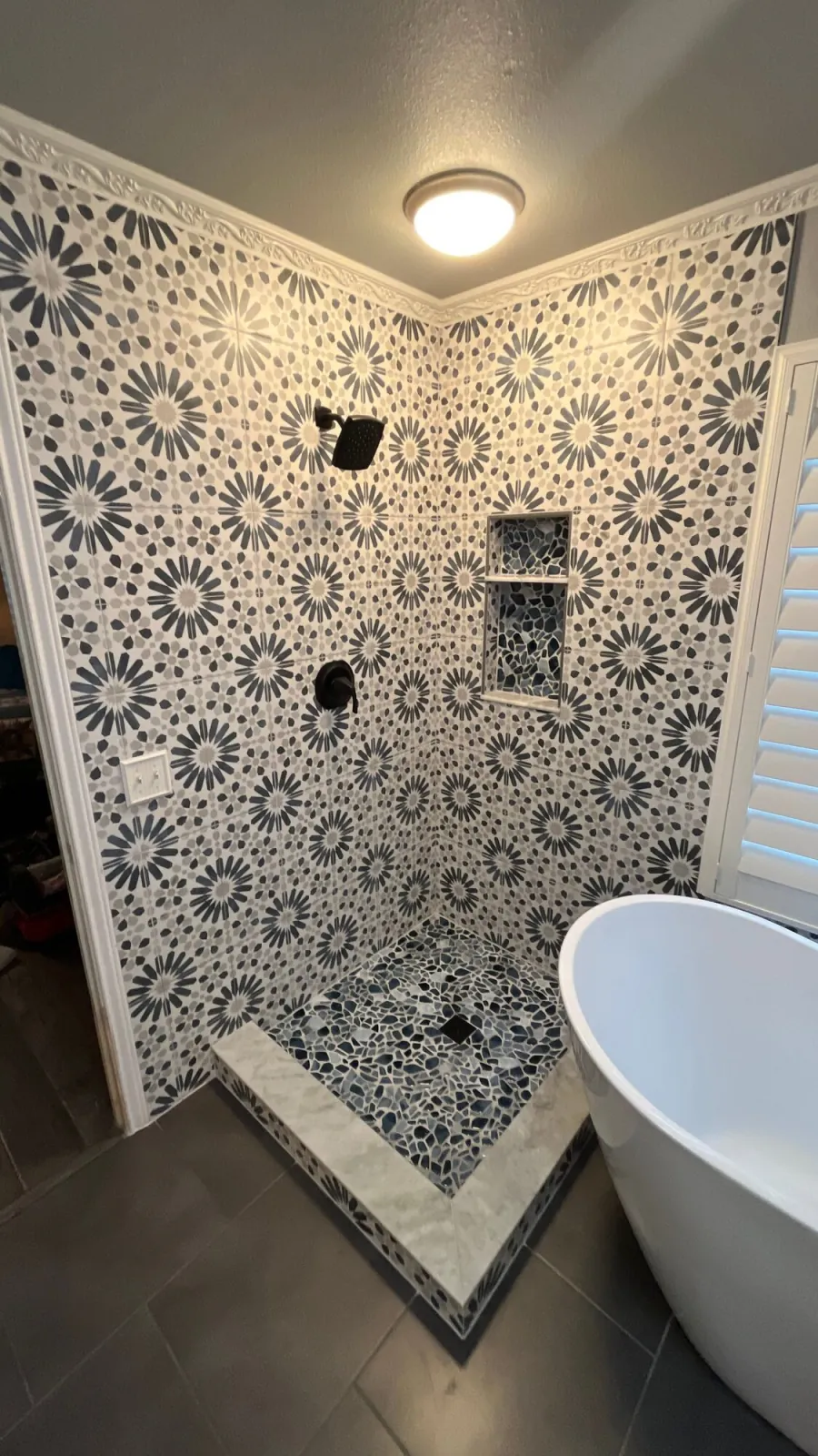 Shower wall in bold patterned tile beside the freestanding tub
