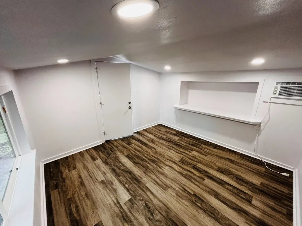 Wide view of the studio showing the shelf run and the entry door