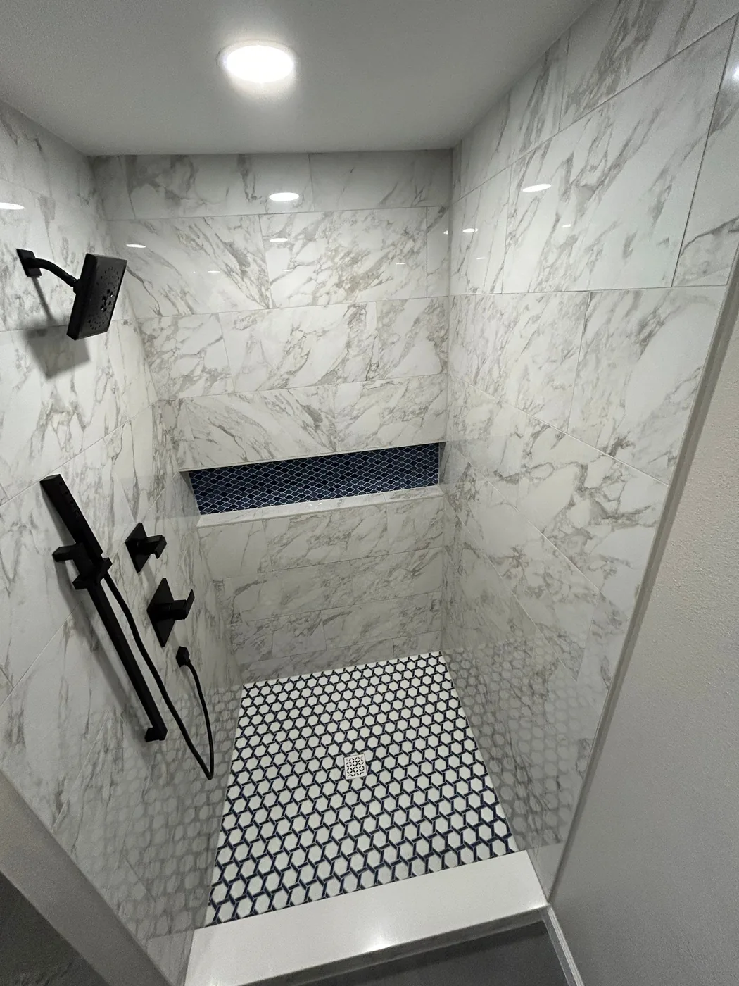 Shower seen from the entry, rain head overhead and the mosaic niche set into the tile