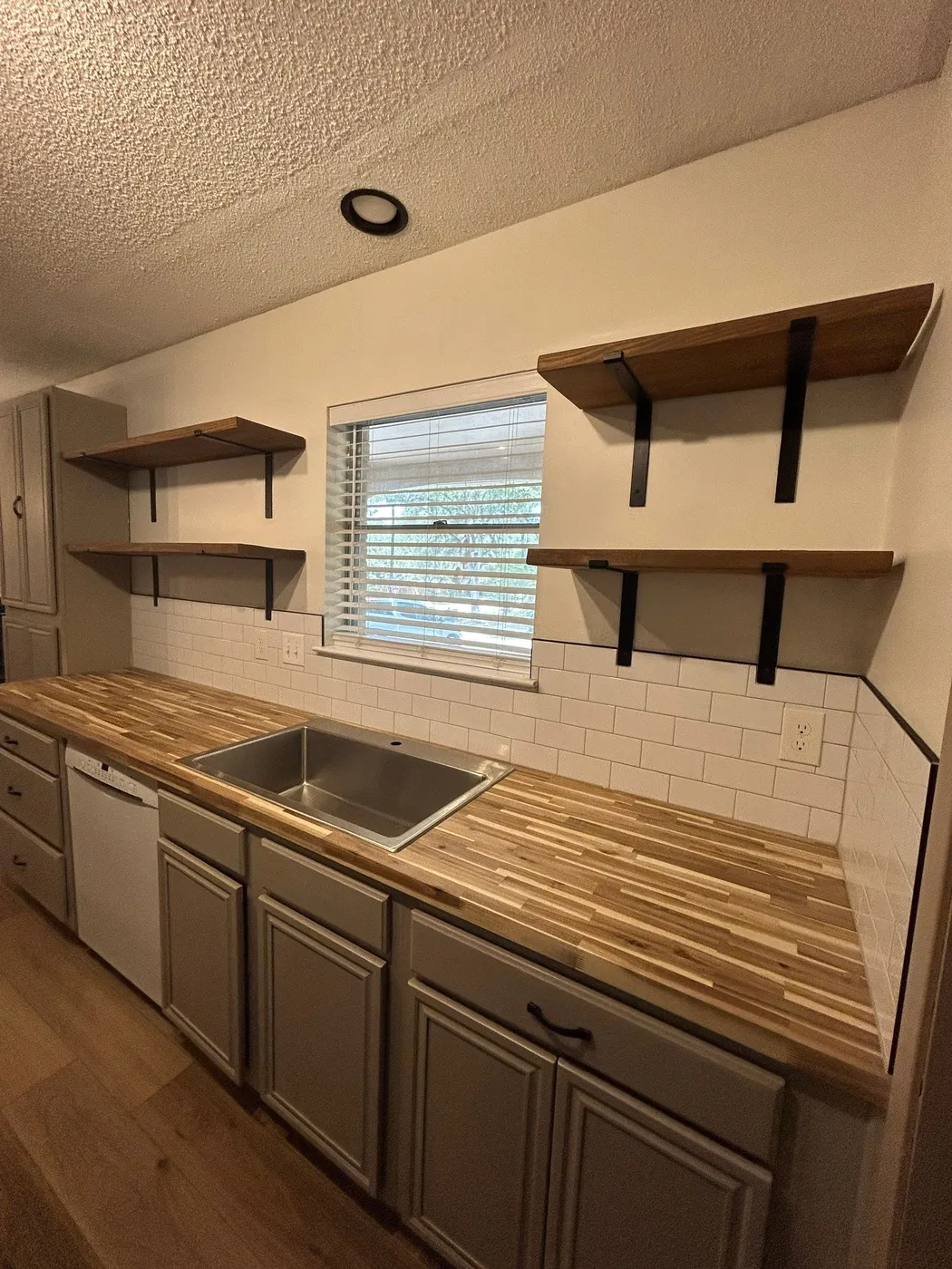 Butcher-block counter run with open wood shelving and the new subway backsplash
