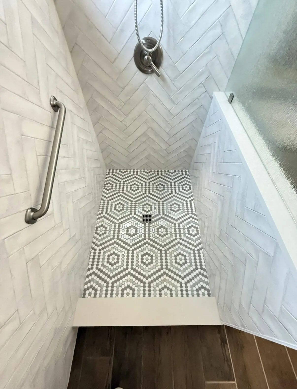 Looking down into the shower at the hexagon mosaic floor and herringbone walls